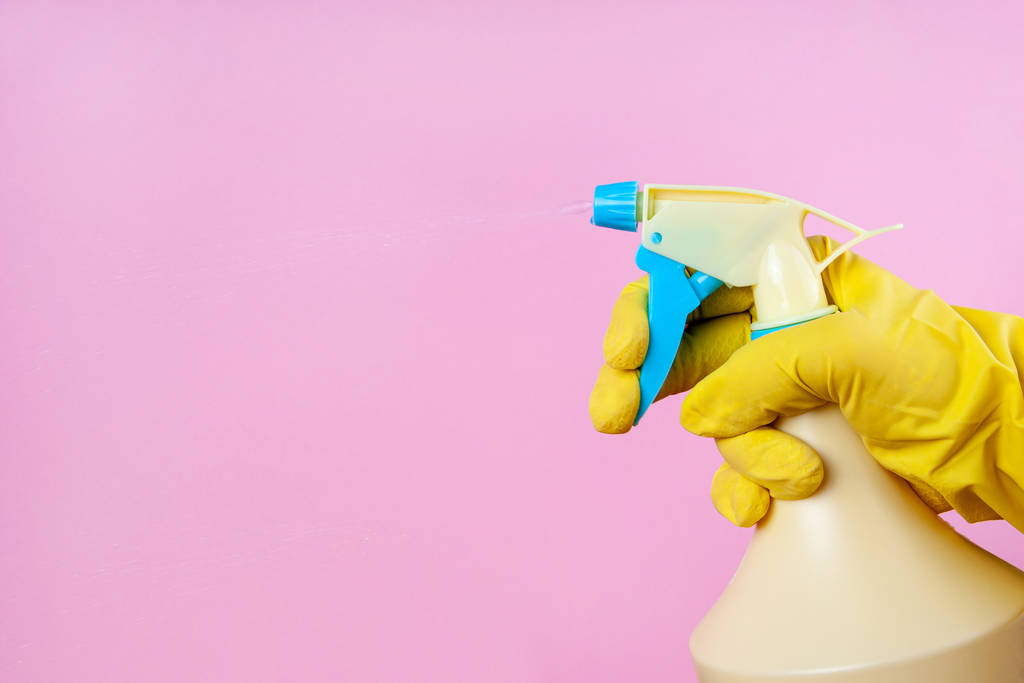 Gloved hand sprays out of a spray bottle on a pink background, copy space, mock up - Photo, Image