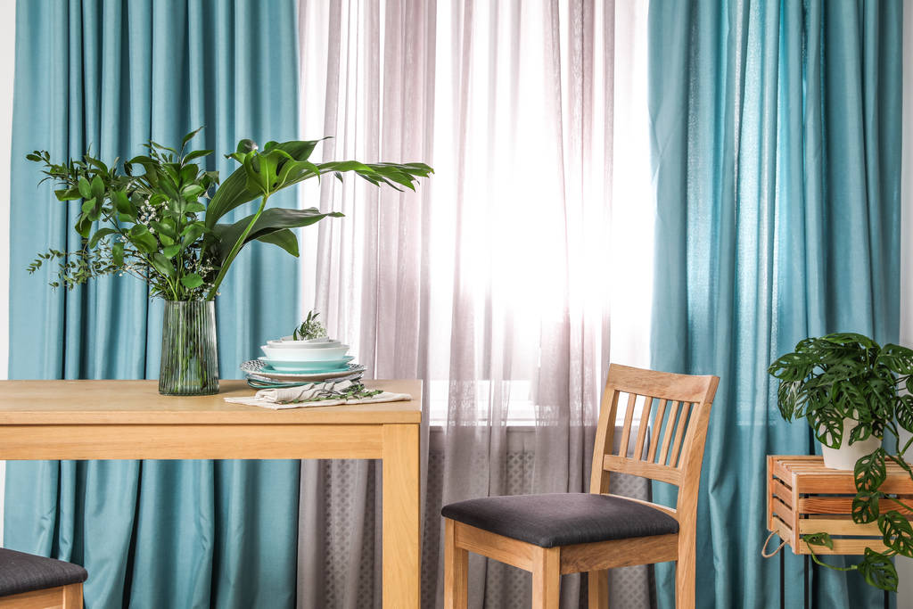 stilvoller Tisch und Stuhl aus Holz in Fensternähe mit eleganten Vorhängen - Foto, Bild