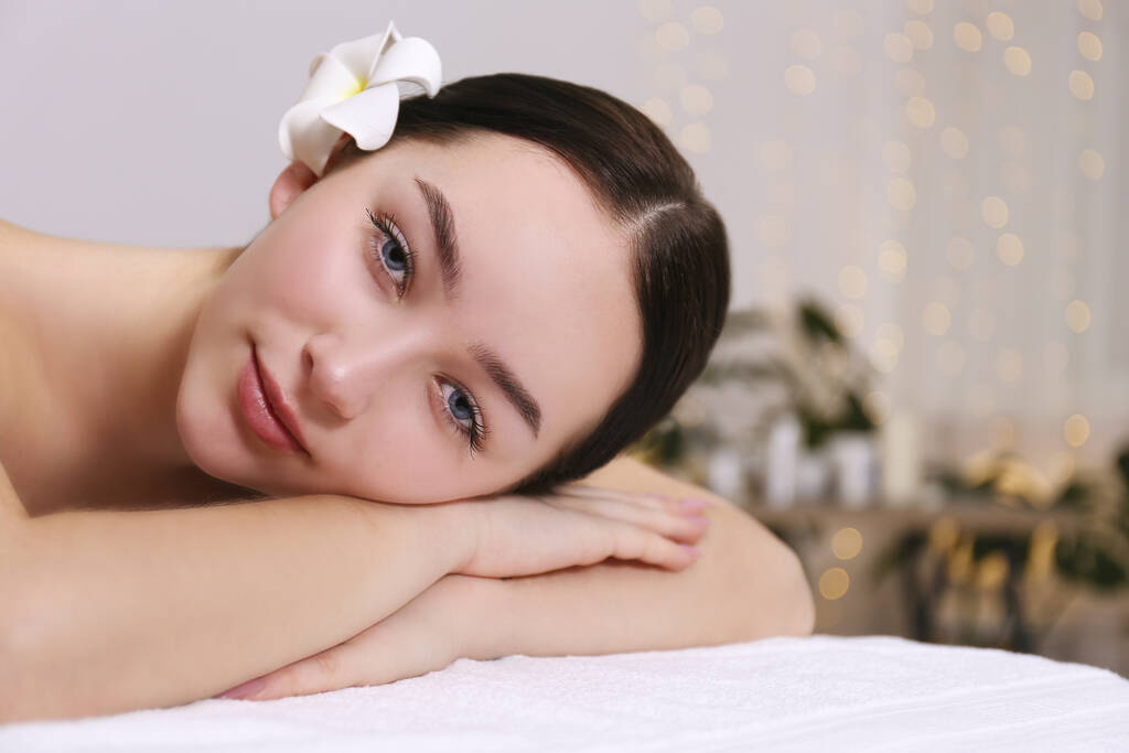 brünette Frau mit entspanntem Gesichtsausdruck auf einem Massagetisch liegend. - Foto, Bild