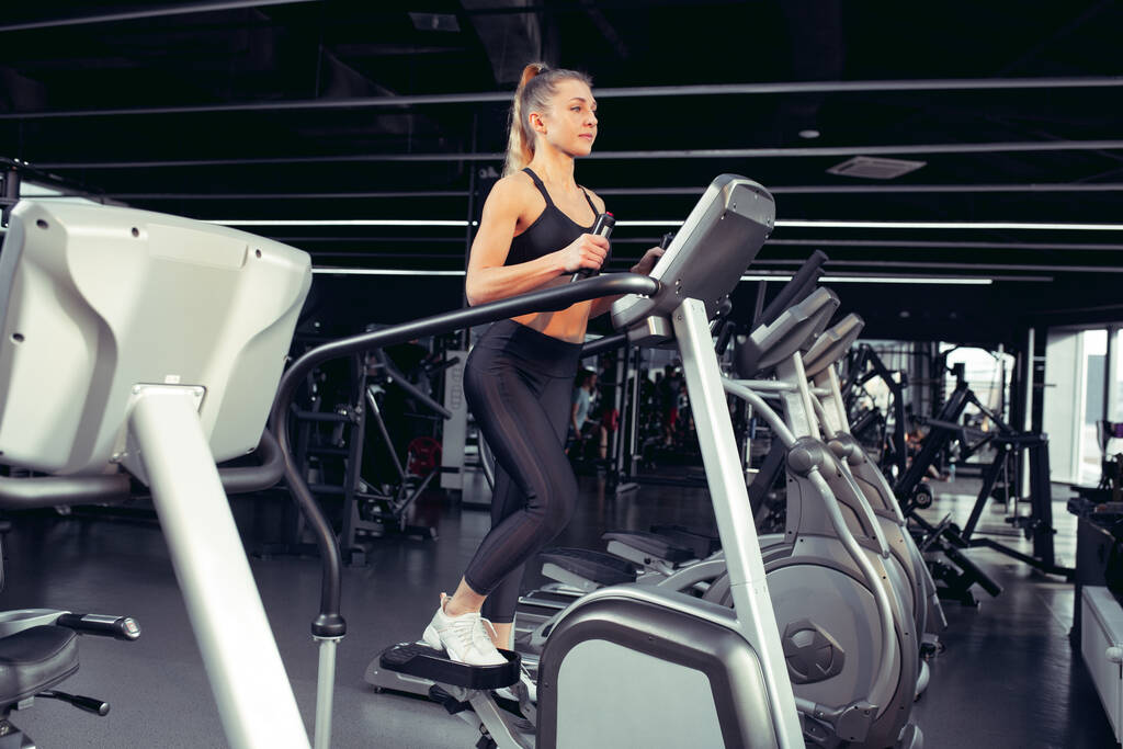 L'athlète féminine s'entraîne dur dans la salle de gym. Concept de forme physique et de vie saine. - Photo, image