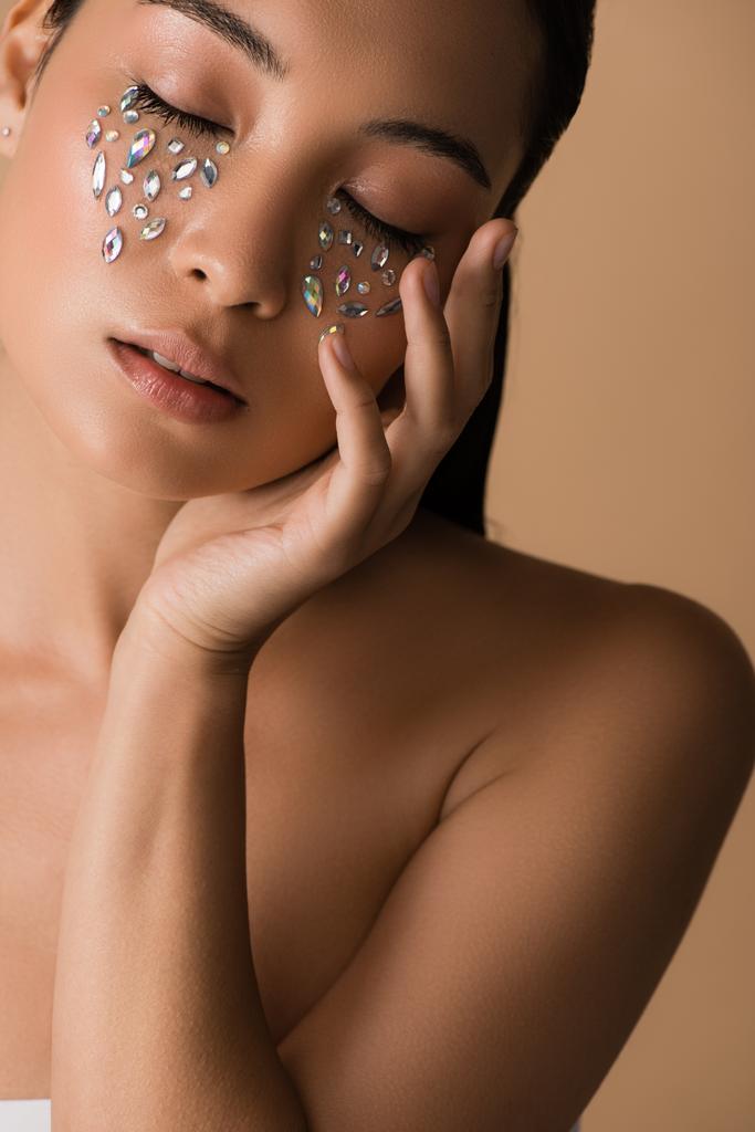 kaunis alaston aasialainen tyttö, jolla on suljetut silmät ja strassit kasvot eristetty beige
 - Valokuva, kuva