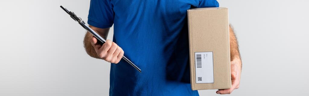 Panoramic shot of courier holding clipboard and cardboard box isolated on grey - Photo, Image