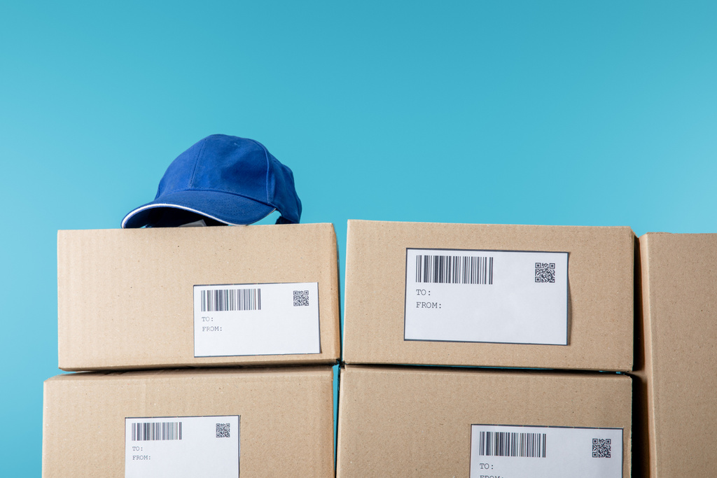 Cap on cardboard boxes with qr and barecodes isolated on blue - Photo, Image
