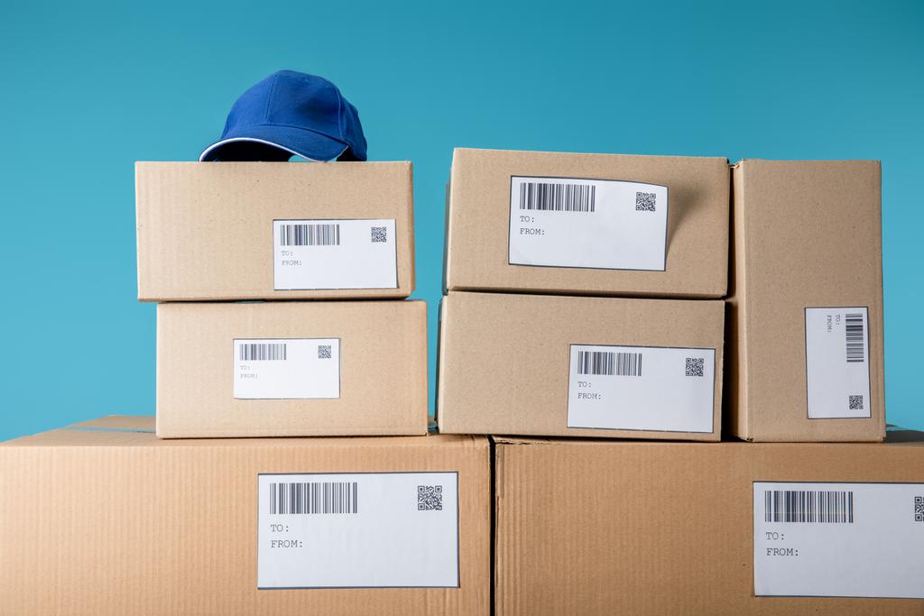 Capuchon sur paquets empilés en carton avec qr et barecodes isolés sur bleu
 - Photo, image