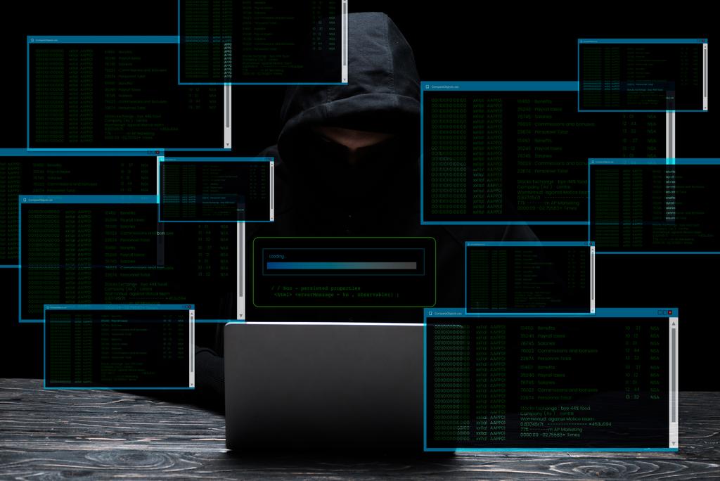 hacker στο καπό χρησιμοποιώντας φορητό υπολογιστή κοντά σε οθόνες με δεδομένα σε μαύρο  - Φωτογραφία, εικόνα