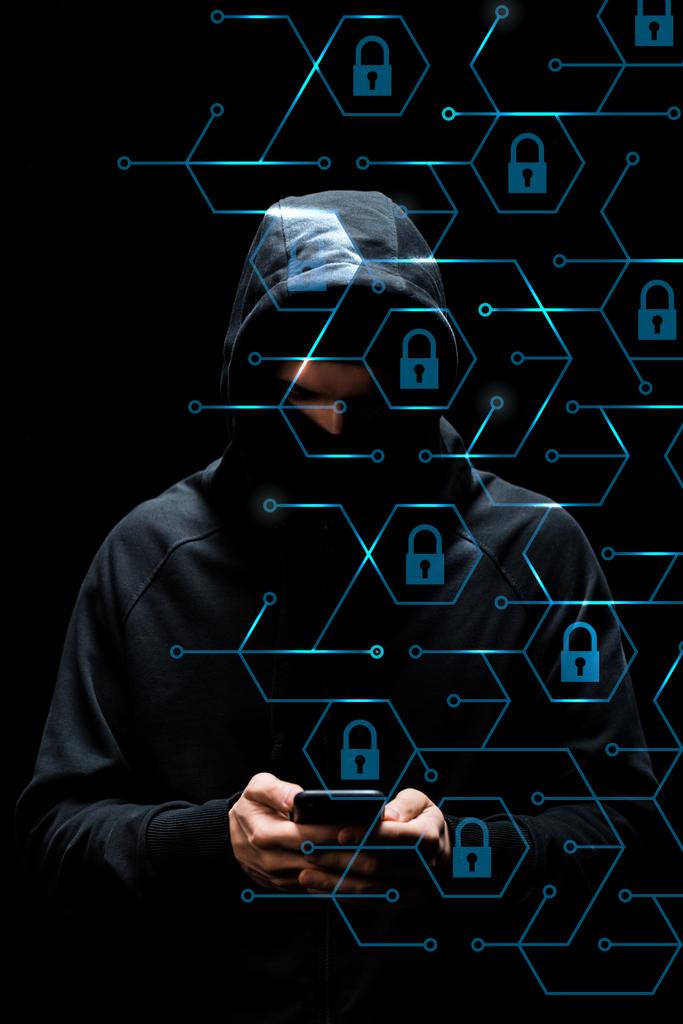 хакер в капюшоне с помощью смартфона возле висячих замков на черном, концепция кибербезопасности
  - Фото, изображение