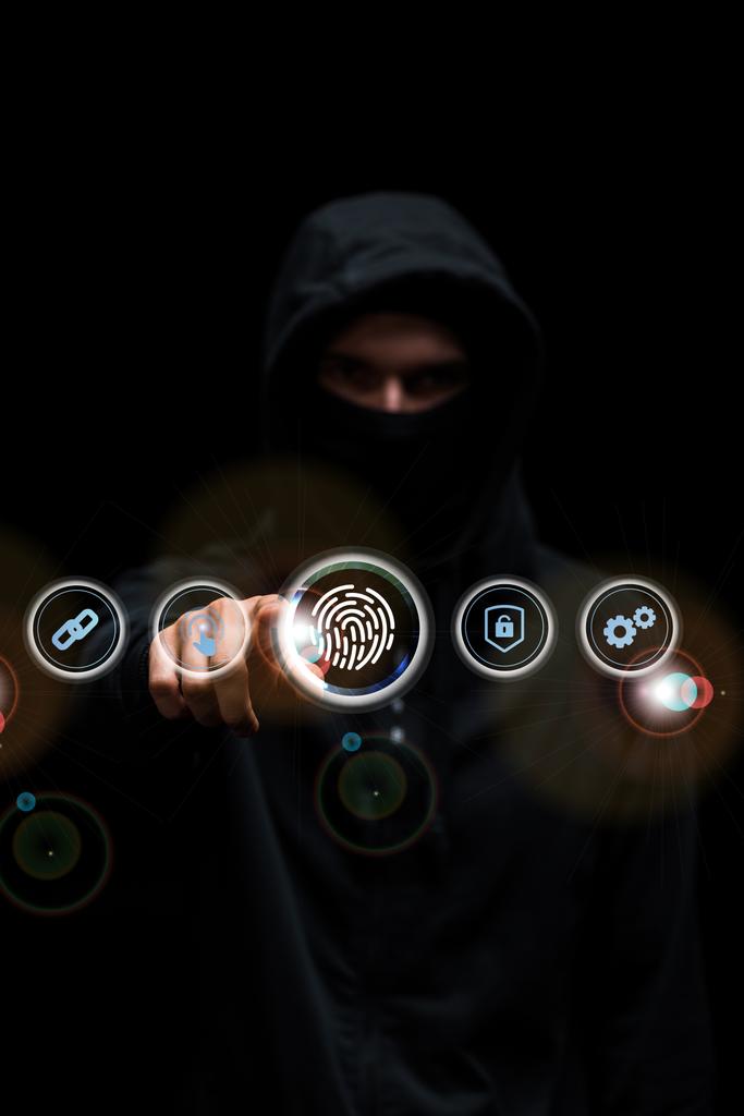 selektiver Fokus des Hackers in Kapuze zeigt mit dem Finger auf Fingerabdruck Web-Symbol auf schwarz  - Foto, Bild