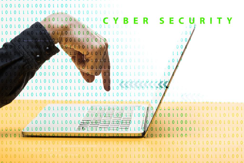 abgeschnittene Ansicht eines Mannes, der mit dem Finger auf Laptop in der Nähe von Cyber-Security-Schriftzug auf Weiß zeigt  - Foto, Bild