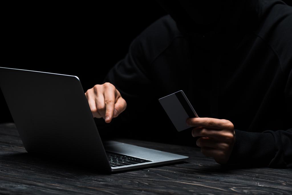 Bilgisayarı kullanan bilgisayar korsanının eklenmiş görüntüsü kredi kartını siyah ekranda izole ederken  - Fotoğraf, Görsel