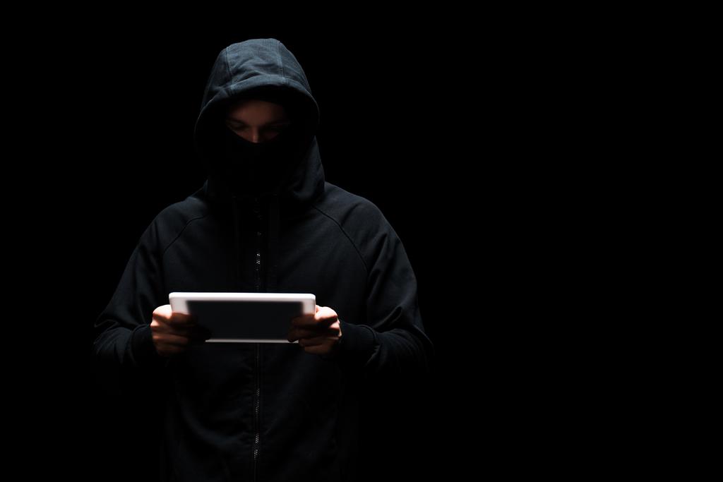 Siyah üzerine izole edilmiş dijital tablet kullanan kapüşonlu ve maskeli anonim hacker  - Fotoğraf, Görsel