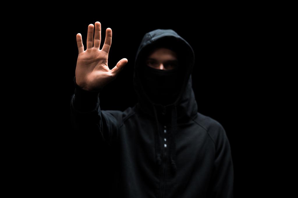 вибірковий фокус анонімного хакера в капюшоні з витягнутою рукою ізольовано на чорному
  - Фото, зображення