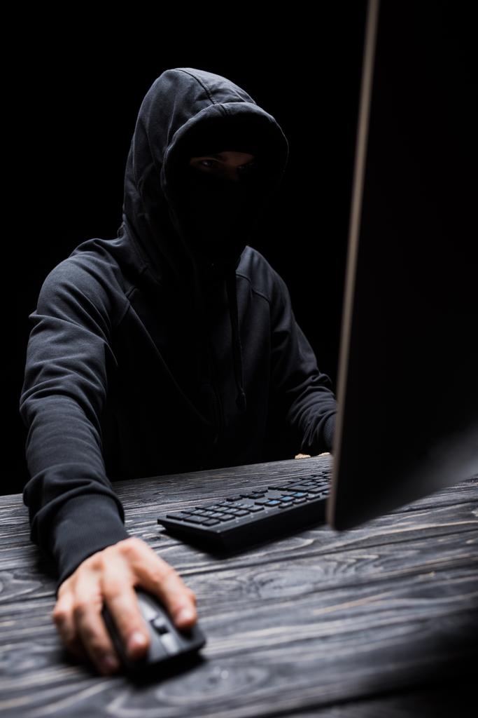 enfoque selectivo de hacker en la capucha utilizando el ordenador aislado en negro
  - Foto, imagen