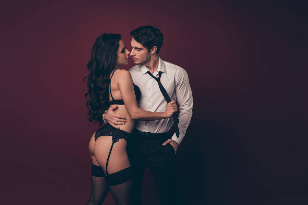 Profil zdjęcie przetargu para dwa ludzie partnerzy macho mąż trzymać nagie postać czarny bikini pani żona zdjąć jego garnitur ciągnąc krawat pocałunek przyjemność odizolowany bordowy kolor tło - Zdjęcie, obraz