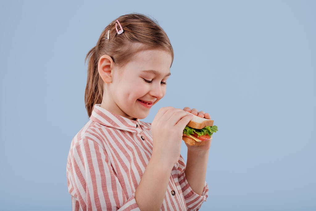 Menina com sanduíche na mão. vista de perfil
, - Foto, Imagem