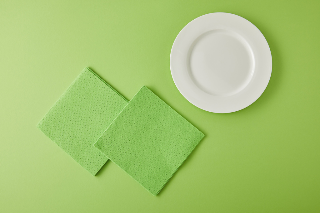 πάνω όψη του λευκού πιάτου και κουρέλια για πλύσιμο πιάτων στο πράσινο - Φωτογραφία, εικόνα