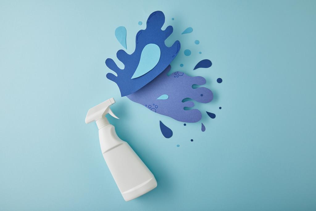 Üst görünüm kompozisyonu sprey şişesi ve mavi üzerine kağıttan yapılmış mavi su sıçramaları. - Fotoğraf, Görsel