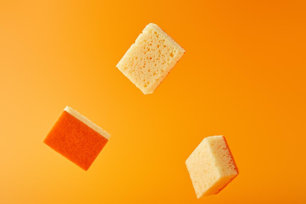 Gelbe Schwämme zum Geschirrspülen isoliert auf Orange - Foto, Bild