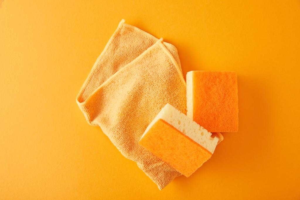 Lappen und gelbe Schwämme für die Hausreinigung auf orange - Foto, Bild