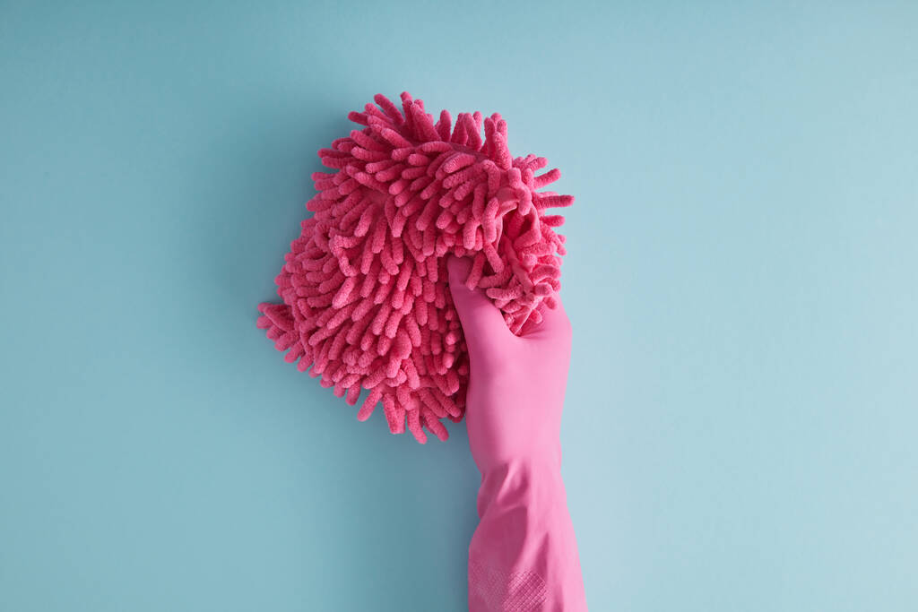 bovenaanzicht van huishoudster in rubber handschoen met roze vod op blauw  - Foto, afbeelding