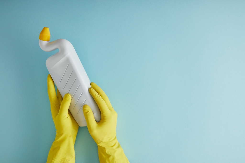 vue recadrée de la femme de ménage en gants de caoutchouc jaune tenant bouteille avec WC nettoyant sur bleu
 - Photo, image
