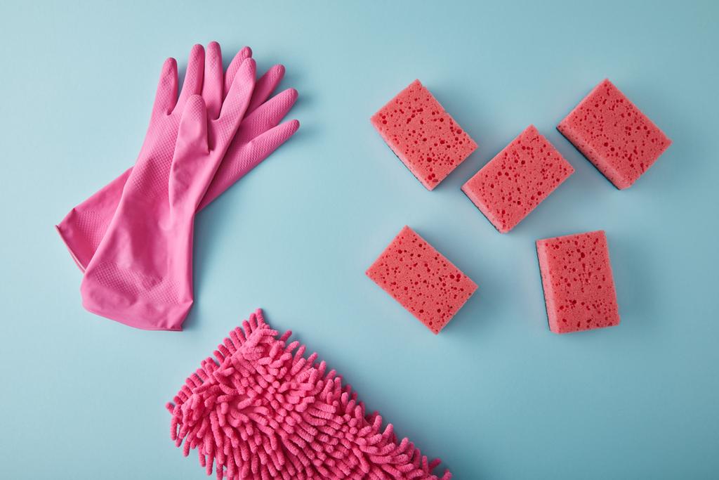 Ansicht von rosa Gummihandschuhen, Lappen und Schwämmen für die Hausreinigung auf blau - Foto, Bild