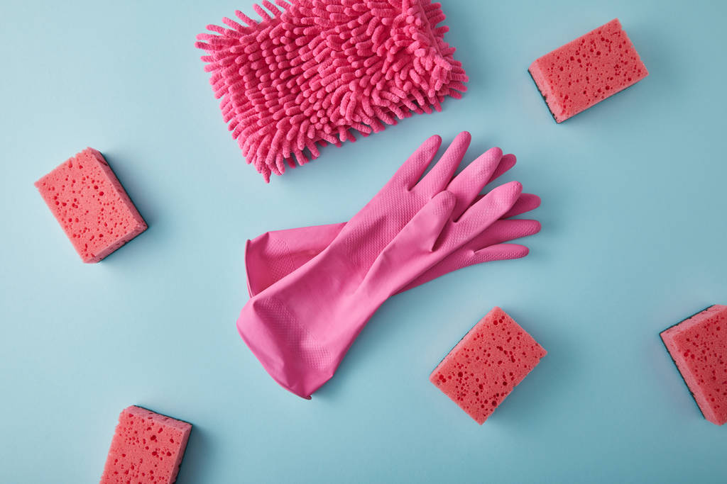 vista superior de pano rosa, luvas de borracha e esponjas para limpeza da casa em azul
 - Foto, Imagem
