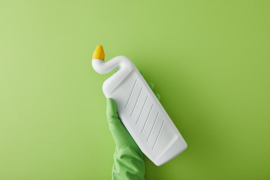 vue du dessus de la femme de ménage dans une bouteille à gants en caoutchouc avec nettoyant pour toilettes sur vert
  - Photo, image