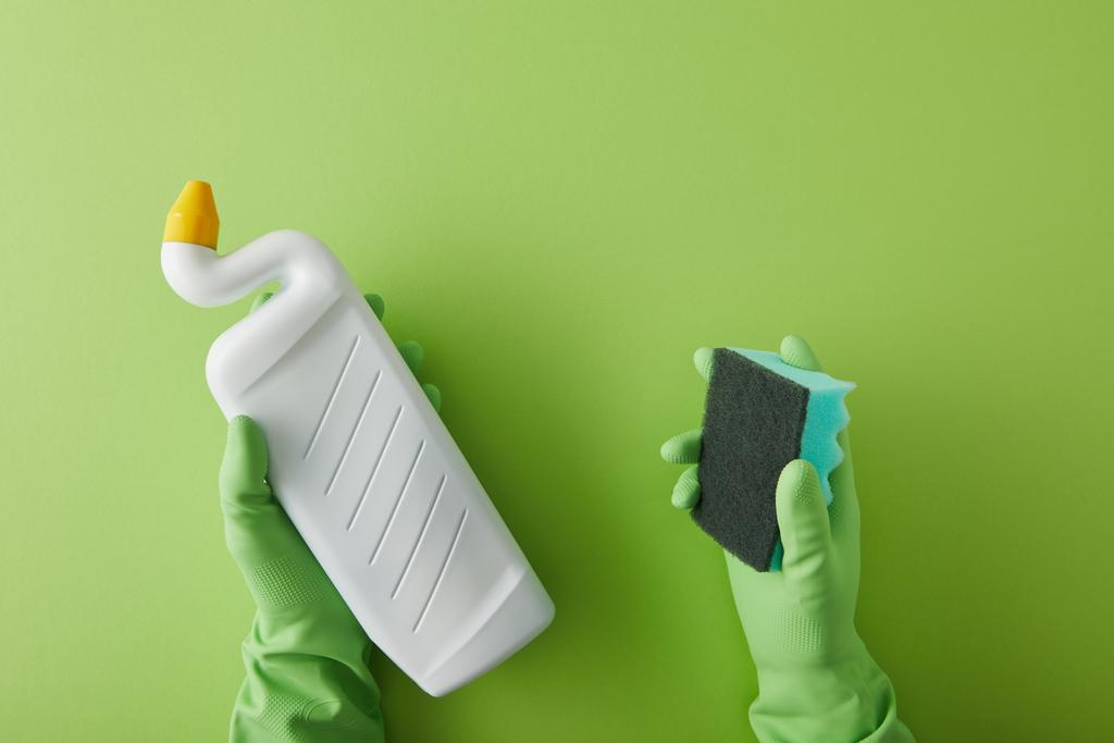 Lastik eldivenli, elinde sünger ve şişeyle yeşil üzerine tuvalet temizleyicisi olan hizmetçi manzarası.  - Fotoğraf, Görsel