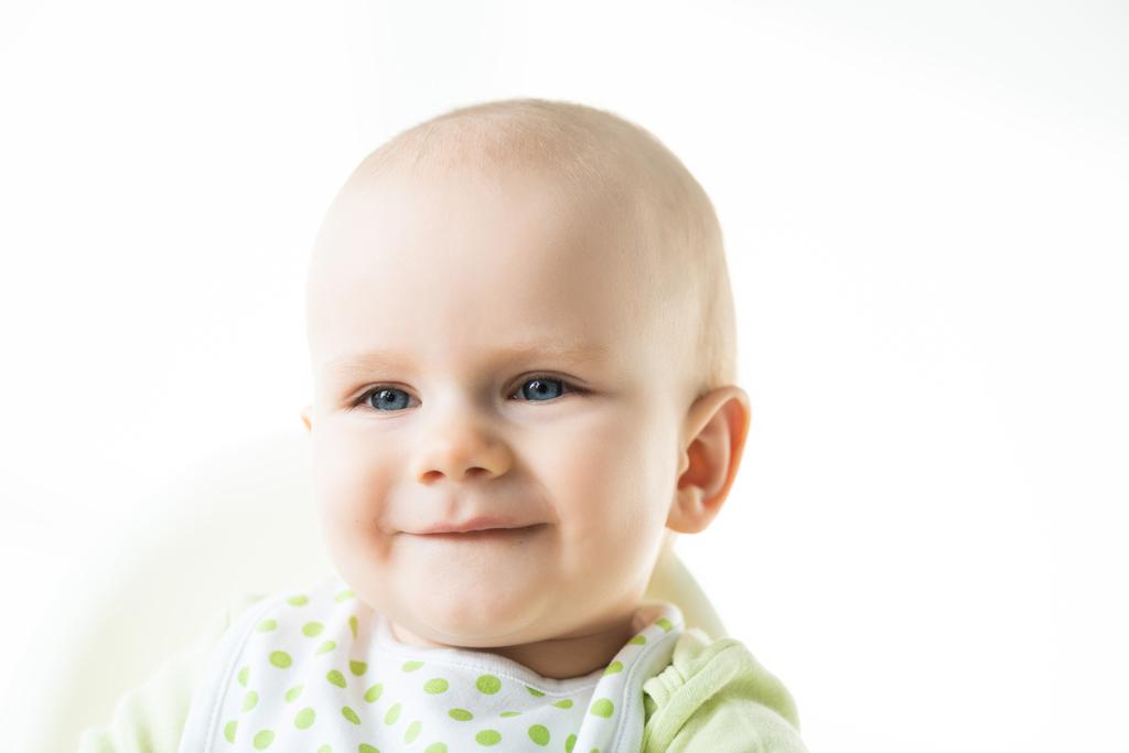 Bébé souriant sur chaise d'alimentation regardant loin isolé sur blanc
 - Photo, image