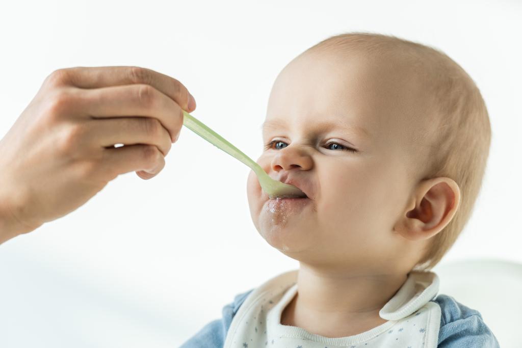 Mother feeding adorable baby with puree on white background - Photo, Image