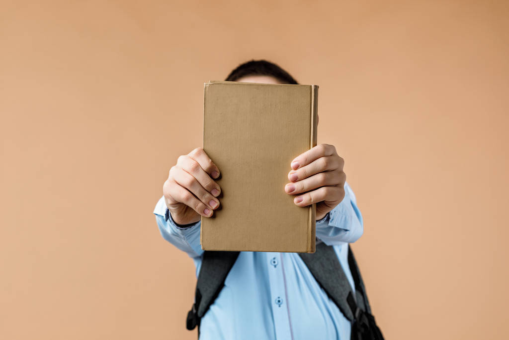 kis vidám iskolás fiú hátizsákkal könyvet ad - Fotó, kép