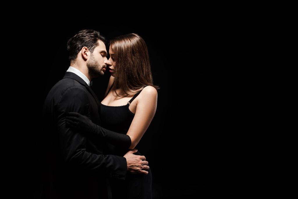 вид збоку гарний чоловік цілує привабливу жінку ізольовано на чорному
  - Фото, зображення