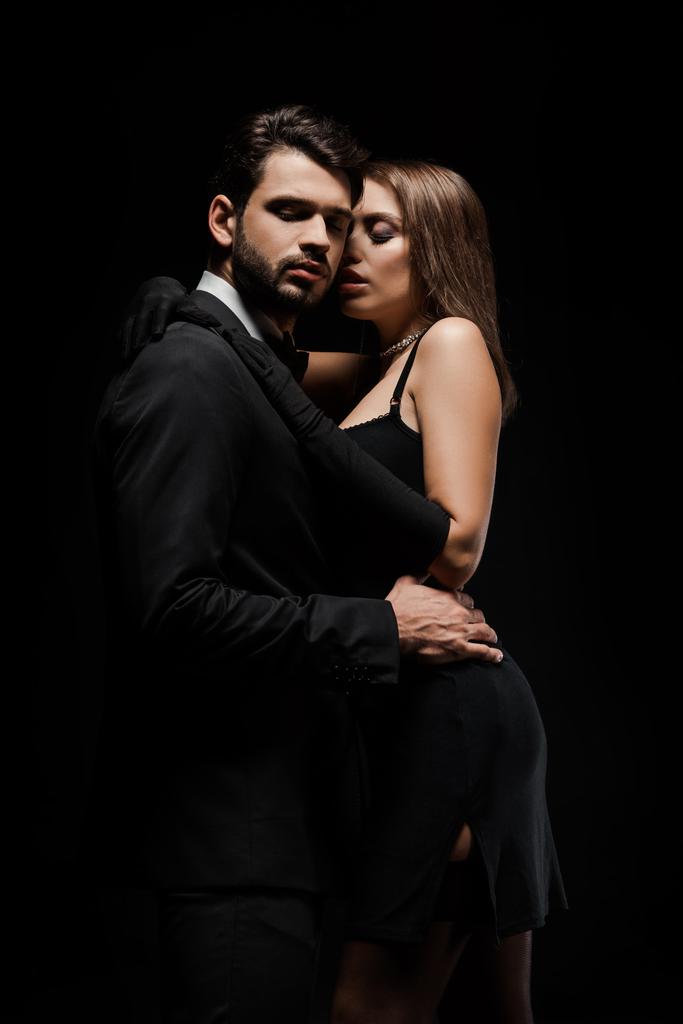 Красивый мужчина обнимает привлекательную женщину в платье, изолированном от черного
  - Фото, изображение