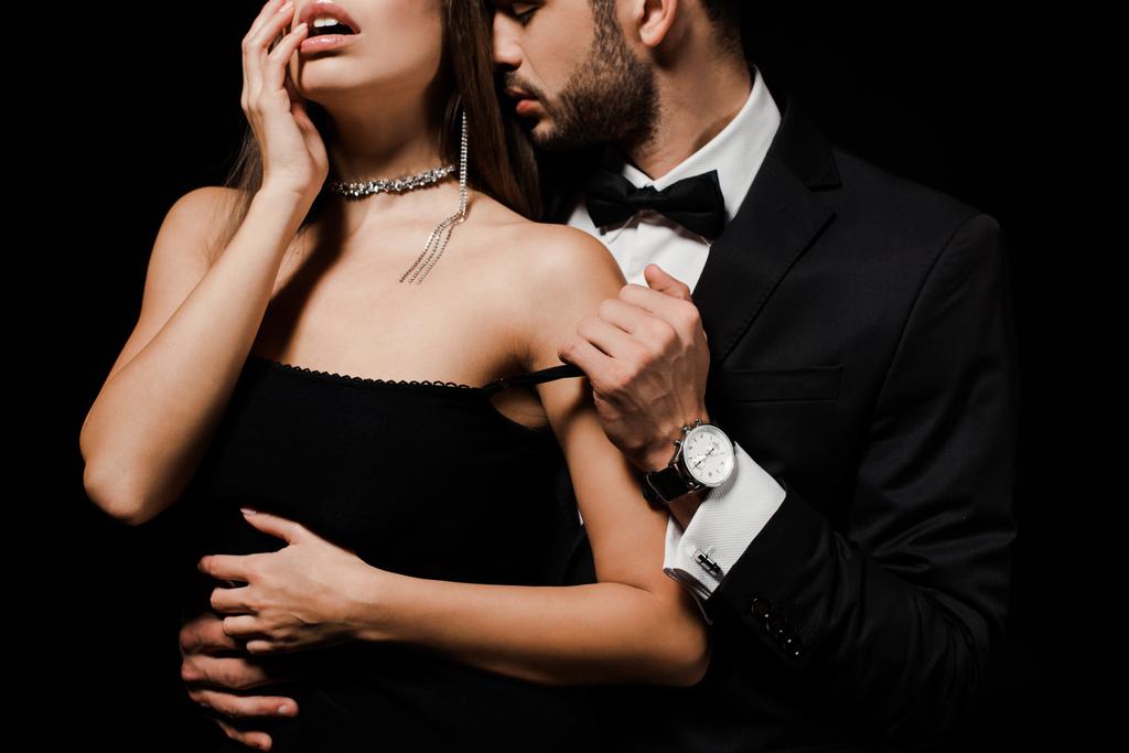 обрізаний вид пристрасного чоловіка, роздягається сексуальна жінка ізольована на чорному
  - Фото, зображення