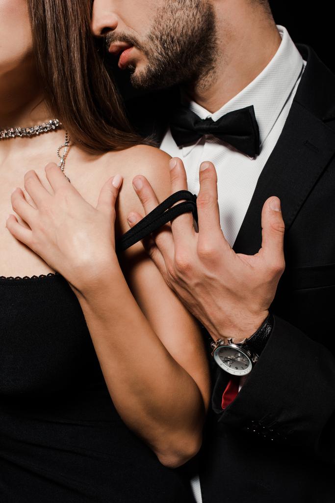 cropped view of passionate man in suit undressing woman isolated on black  - Photo, Image