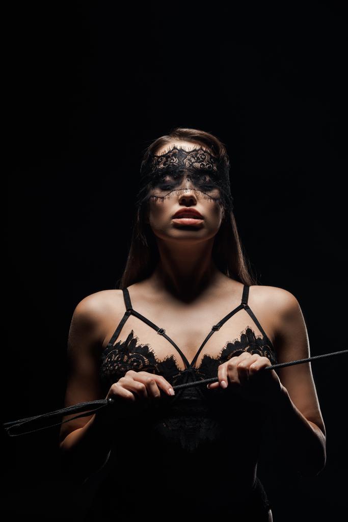 ελκυστική και με δεμένα μάτια γυναίκα κρατώντας μαστίγιο μαστίγιο απομονωμένο σε μαύρο - Φωτογραφία, εικόνα