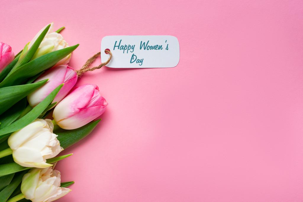 ピンクの表面に紙のラベルに幸せな女性の日のレタリングとチューリップの花束のトップビュー ロイヤリティフリー写真 画像素材