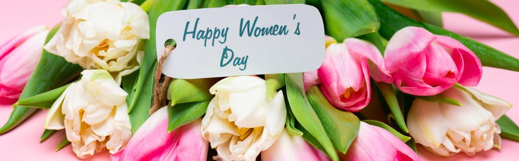 Panoramiczne ujęcie szczęśliwych kobiet dzień napisy na papierze etykieta na bukiet tulipanów na różowym tle - Zdjęcie, obraz