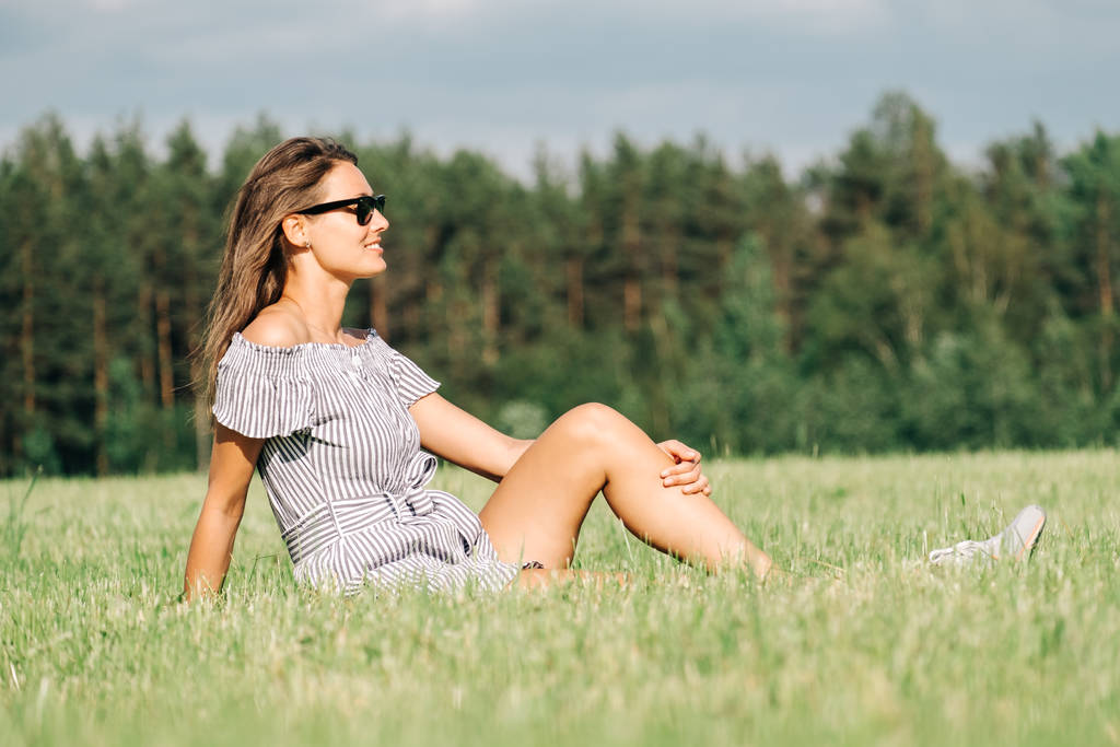 Žena v šatech sedí na zelené trávě pole - Fotografie, Obrázek