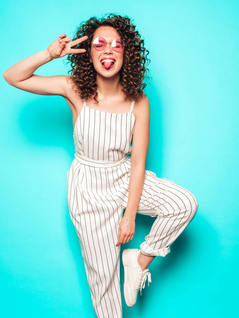 Porträt der schönen lächelnden Modell mit Afro-Locken-Frisur gekleidet in Sommer-Hipster-Kleidung.sexy unbeschwertes Mädchen posiert in der Nähe der blauen Wand.trendy lustig und positiv Frau - Foto, Bild