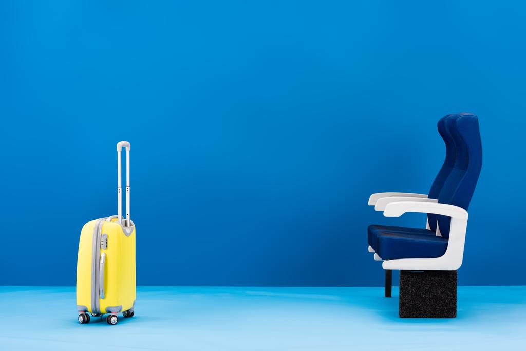 yellow travel bag and seats on blue background  - Photo, Image