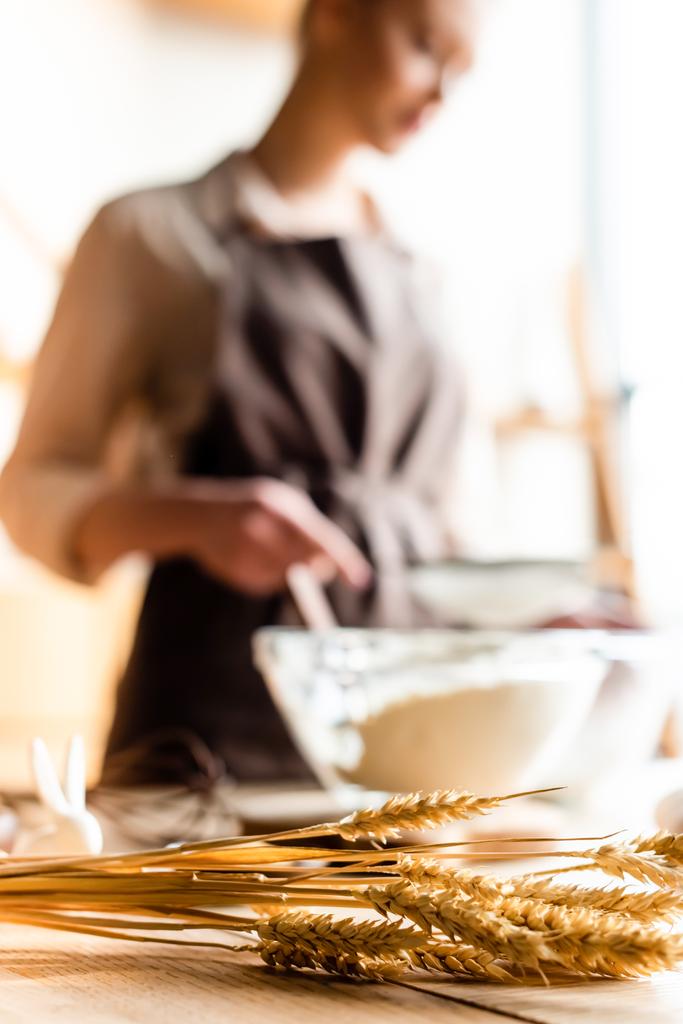 台所で調理する女性の近くの小麦の選択的な焦点  - 写真・画像