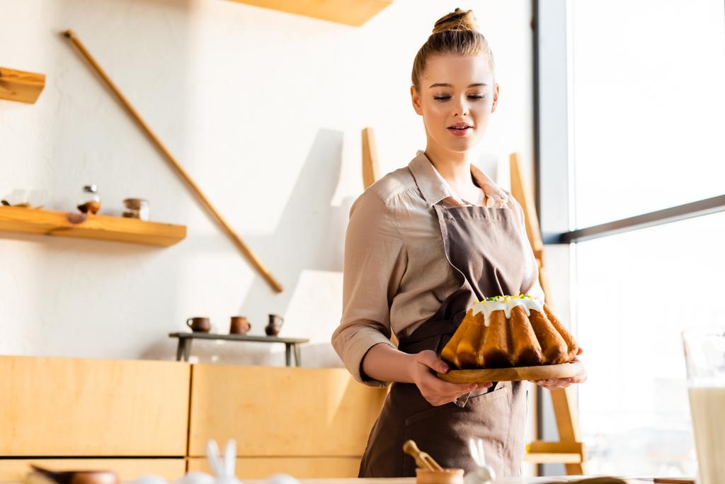 attrayant femme dans tablier tenant gâteau de Pâques cuit au four
  - Photo, image