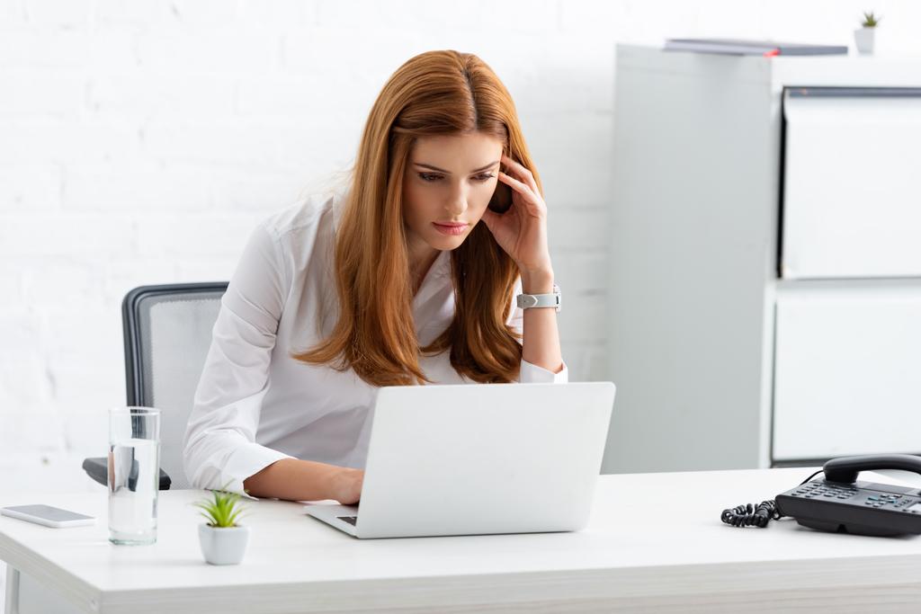 Atrakcyjna bizneswoman pracująca w laptopie przy szklance wody na stole - Zdjęcie, obraz