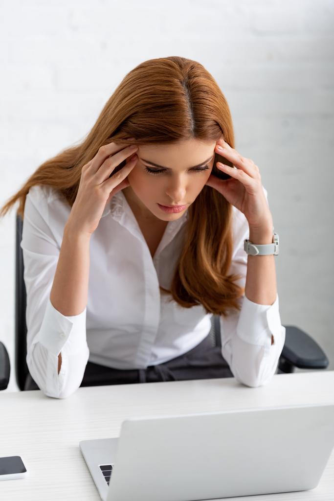 Femme d'affaires pensive avec les mains près de la tête regardant ordinateur portable sur la table
 - Photo, image