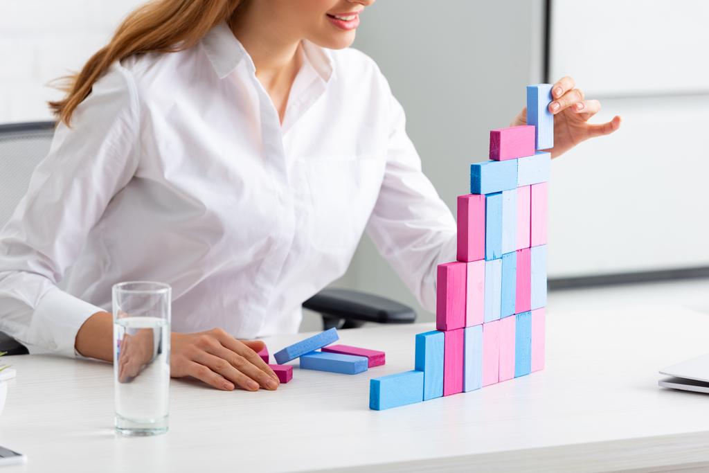Vista ritagliata di donna d'affari sorridente accatastamento piramide di marketing da mattoni sul tavolo
 - Foto, immagini