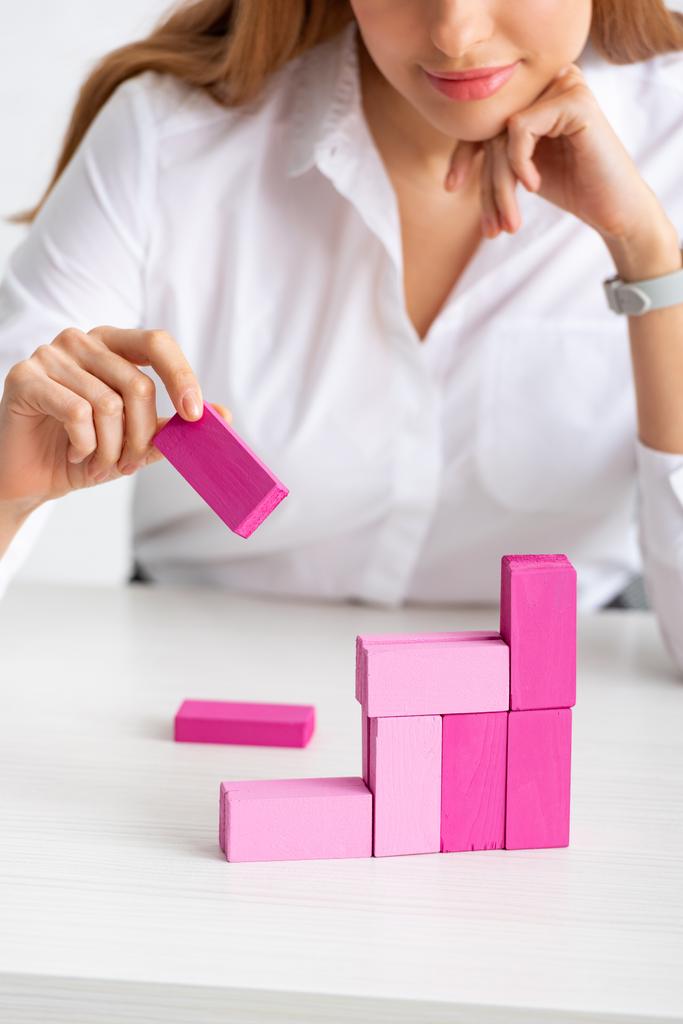 Selective focus of businesswoman stacking marketing pyramid with pink building blocks isolated on grey - Fotoğraf, Görsel
