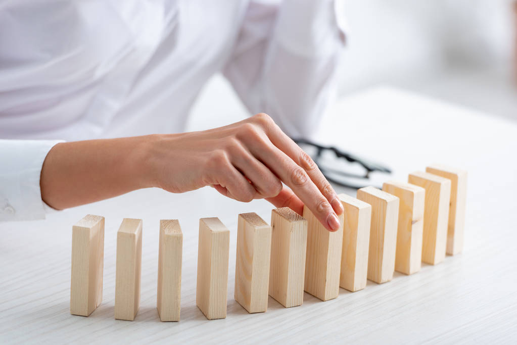 Cropped view of businesswoman playing wooden building blocks at table  - 写真・画像