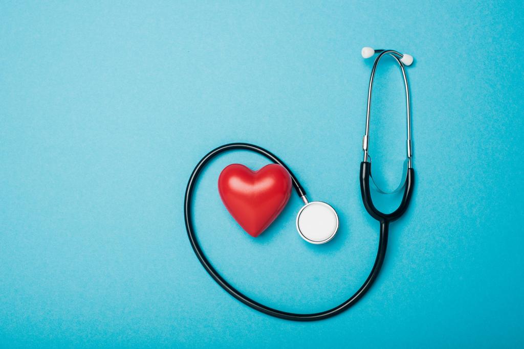 Horní pohled na dekorativní srdce a stetoskop na modrém pozadí, koncept světového dne zdraví - Fotografie, Obrázek