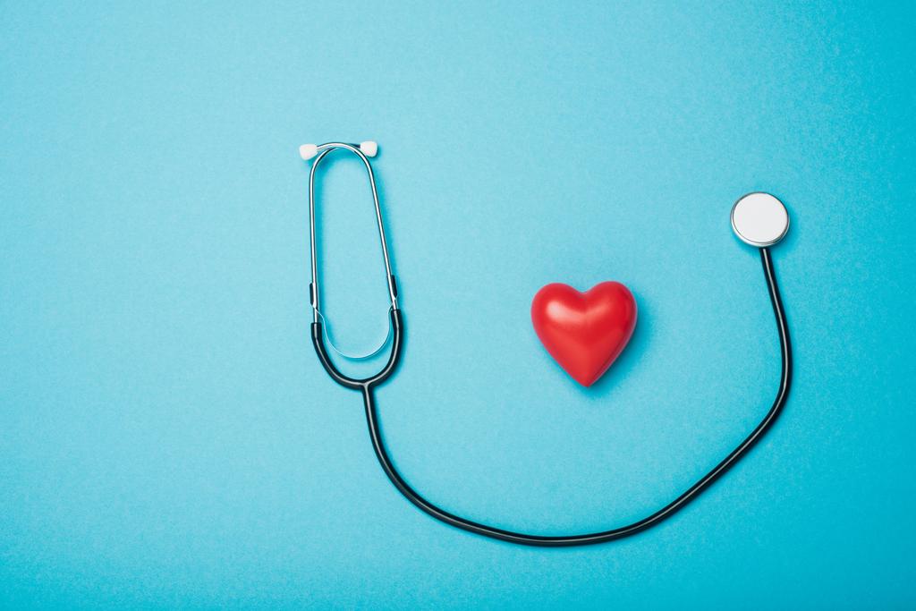 Κάτοψη διακοσμητικής κόκκινης καρδιάς και στηθοσκοπίου σε μπλε φόντο, έννοια παγκόσμια ημέρα υγείας - Φωτογραφία, εικόνα